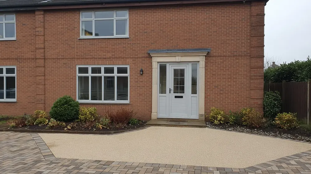 Example image: a buff resin driveway with a paved border outside a detached house